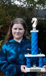Julie stands in a blue tie-dye sweatshirt holding her Student of the Year award.